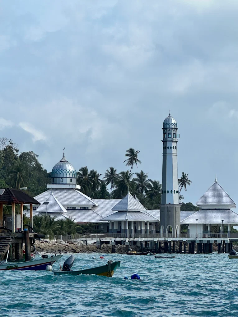 The Floating Mosque on Pulau Perhentian Kecil, officially known as Masjid Al‑Rahman Perhentian, is a small mosque built on pillars above the sea. It is located near the main jetty of the Perhentian Islands in Malaysia. The mosque is known for its peaceful setting and beautiful ocean views. Visitors often stop here to admire the architecture, take photos, or enjoy the calm atmosphere. For Muslim travelers, it is also an important place for daily prayers while visiting the Perhentian Islands.